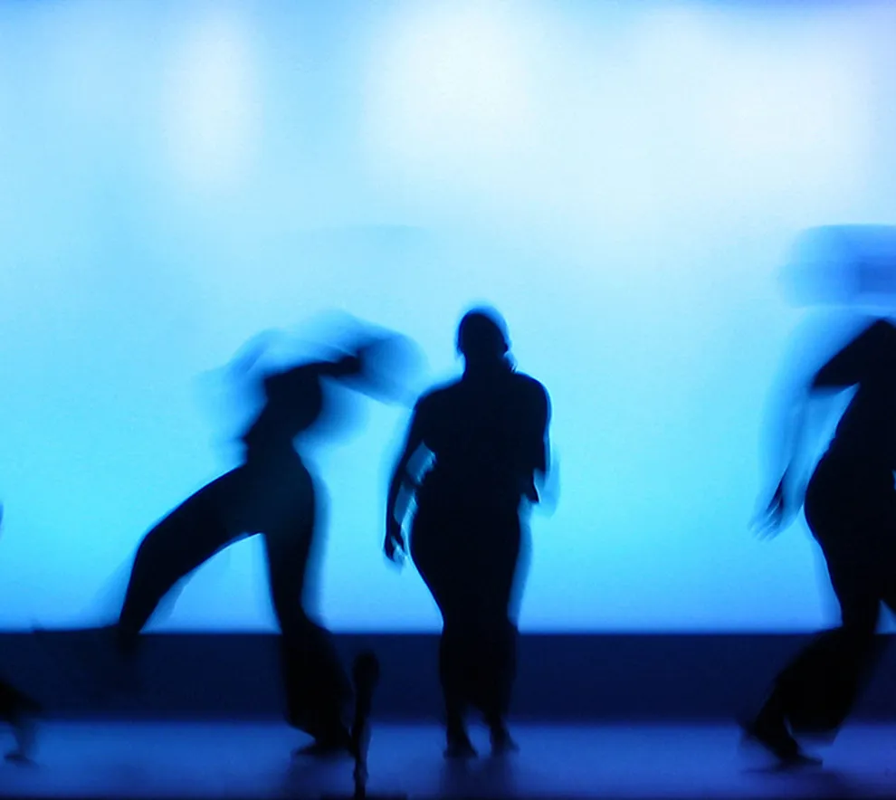 Bilde av dansere på en scene med blått lys