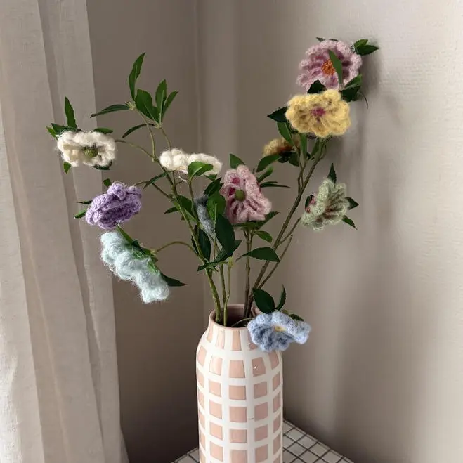 Heklede blomster i duse farger i en vase.