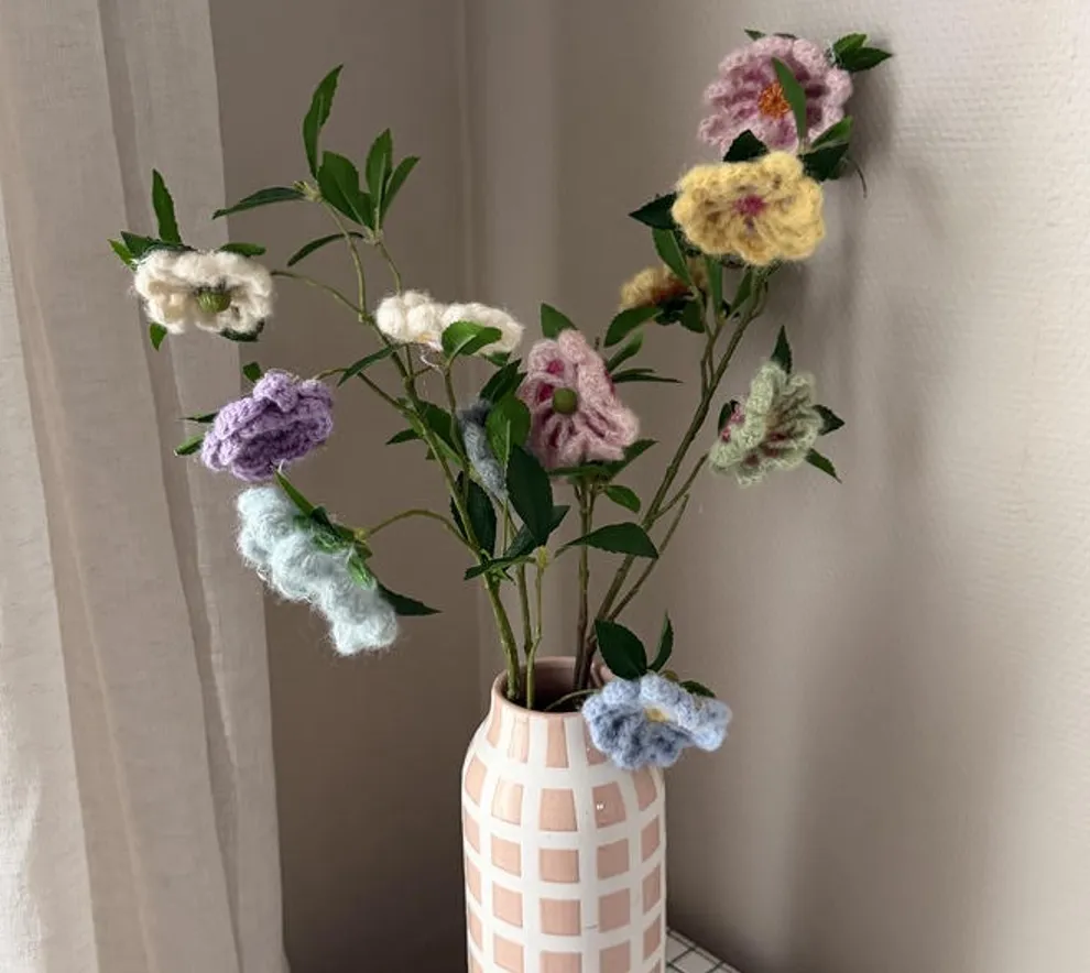 Heklede blomster i duse farger i en vase.