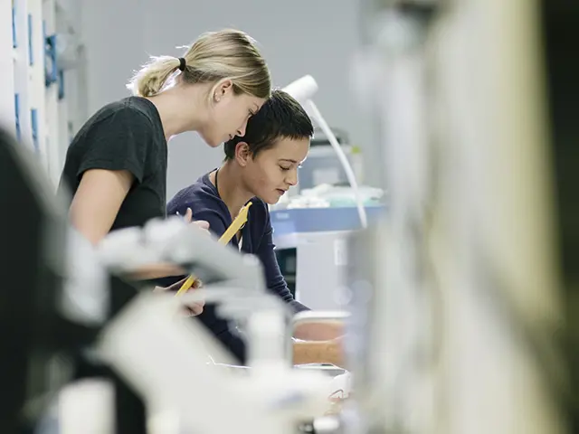 To kvinnelige forskere jobber sammen i et moderne laboratorium, omgitt av avansert medisinsk teknologi og forskningsutstyr.