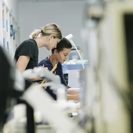To kvinnelige forskere jobber sammen i et moderne laboratorium, omgitt av avansert medisinsk teknologi og forskningsutstyr.