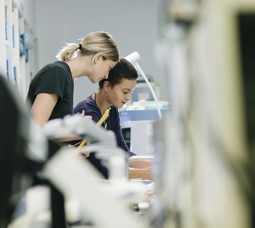 To kvinnelige forskere jobber sammen i et moderne laboratorium, omgitt av avansert medisinsk teknologi og forskningsutstyr.