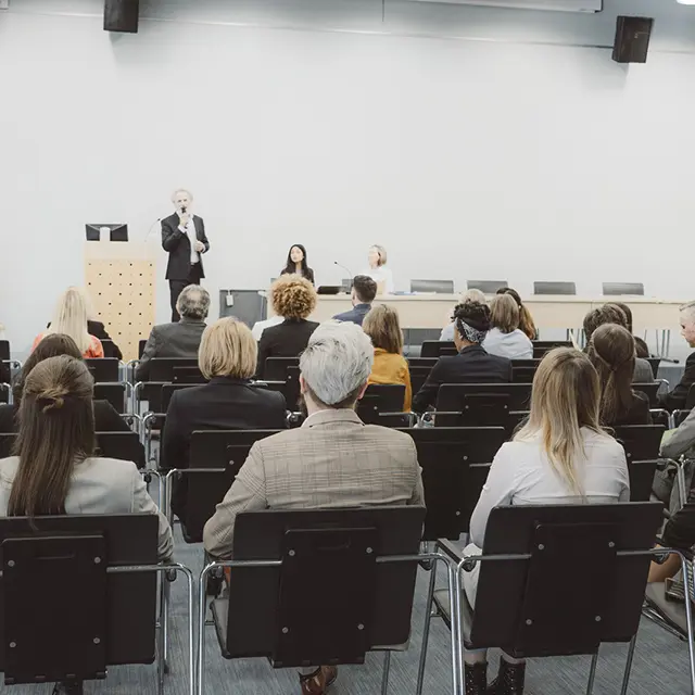Foredragsholder og publikum under seminar eller konferanse i møterom.