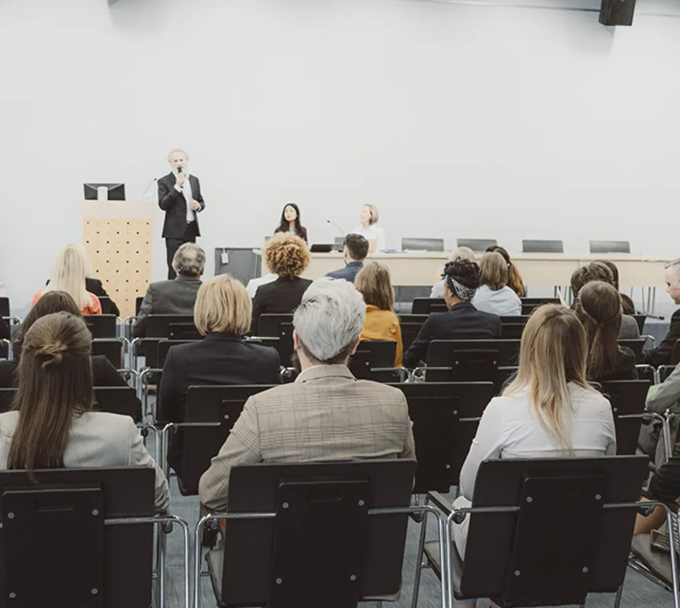 Foredragsholder og publikum under seminar eller konferanse i møterom.
