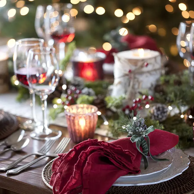 Nærbilde av et bord dekket klart til fest med pynt og røde servietter.