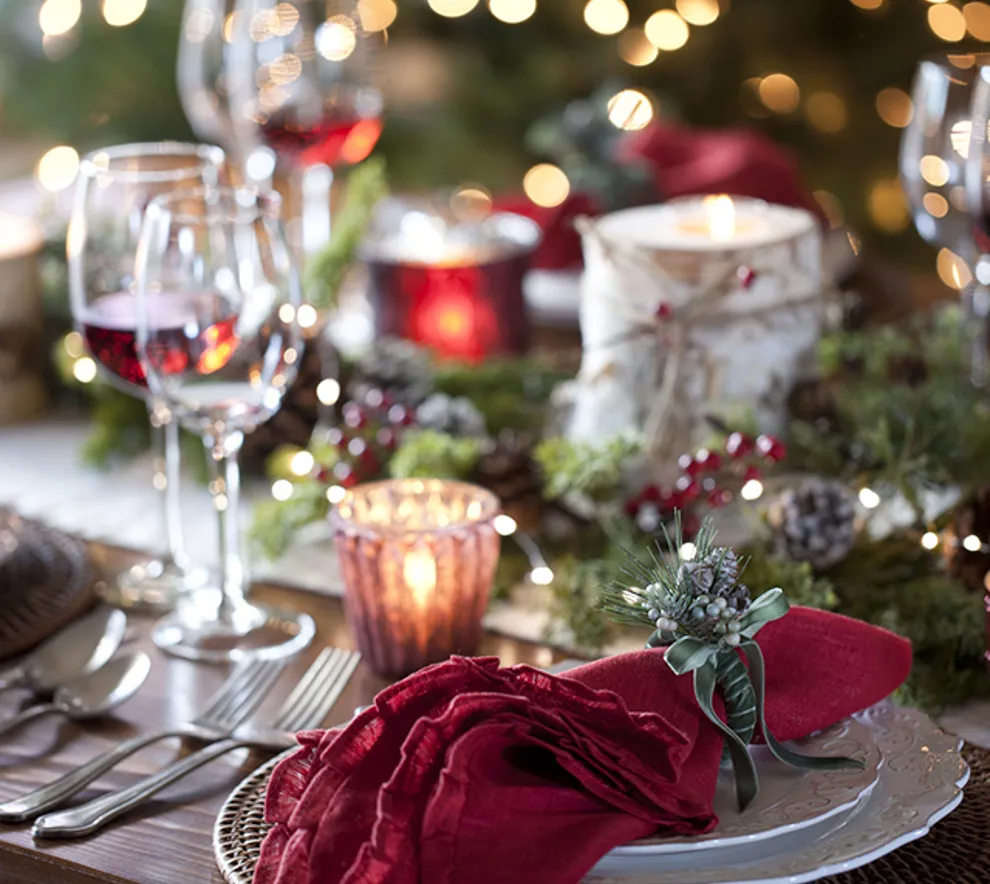 Nærbilde av et bord dekket klart til fest med pynt og røde servietter.