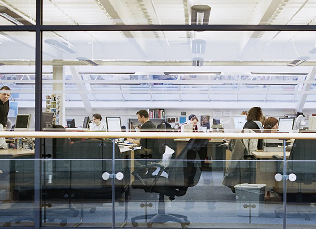 Folk jobber i åpent kontorlandskap i offentlig sektor, foran skjermer og i møte med hverandre.