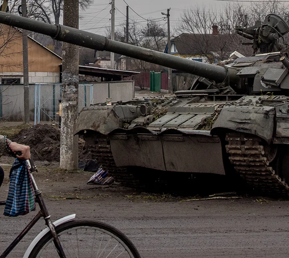 Mann sykler forbi tanks i Ukraina