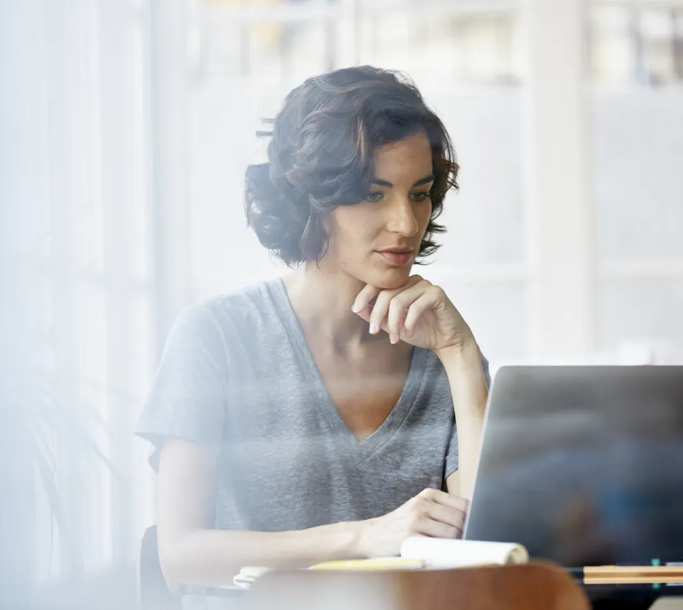 Kvinne jobber fokusert på en laptop.