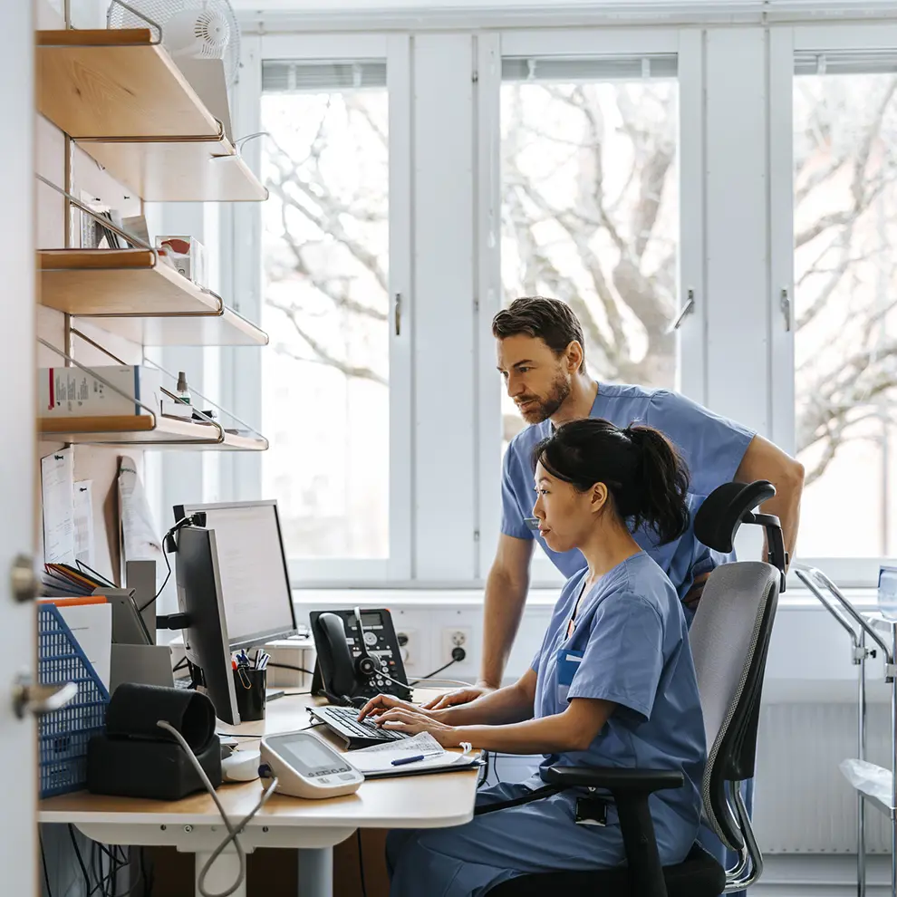 Lege og sykepleier jobber med digitale helsedata på datamaskin i sykehusmiljø
