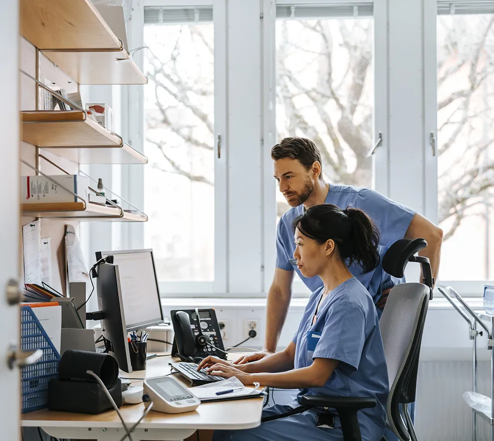 Lege og sykepleier jobber med digitale helsedata på datamaskin i sykehusmiljø