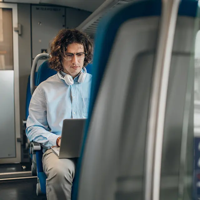 Mann jobber på laptop under togreise – pendling med internett og fleksibelt hjemmekontor.