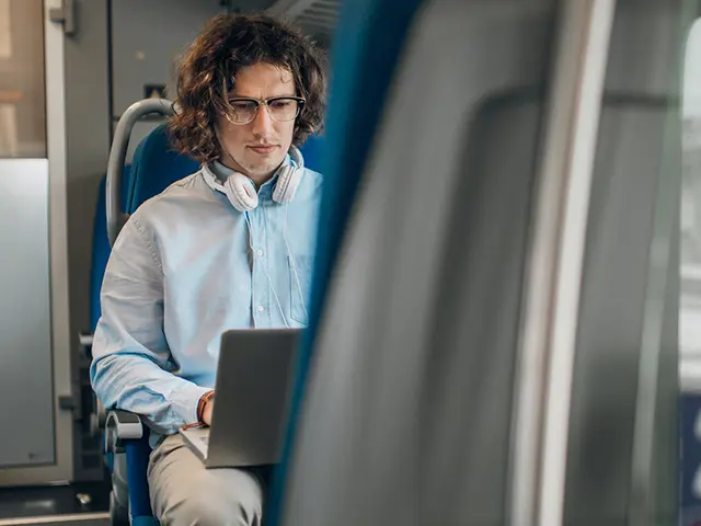 Mann jobber på laptop under togreise – pendling med internett og fleksibelt hjemmekontor.