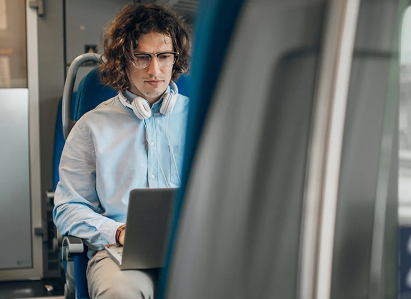 Mann jobber på laptop under togreise – pendling med internett og fleksibelt hjemmekontor.