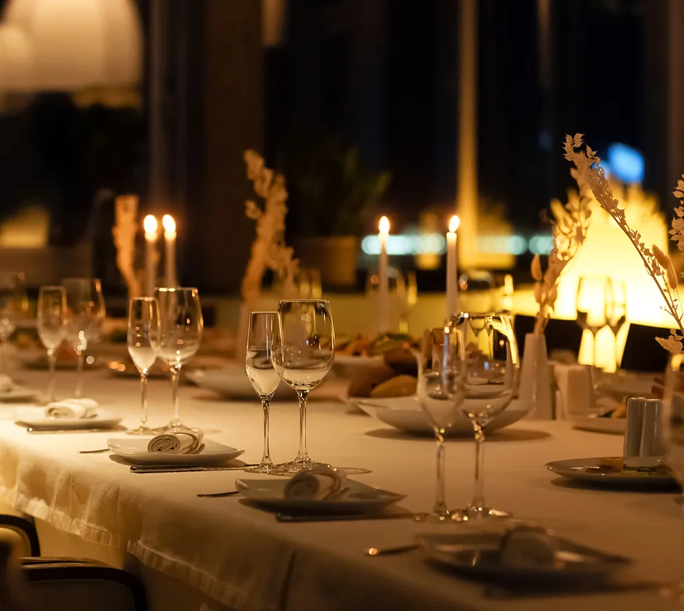Elegant festbord dekket med glass, lys og servise til en høytidelig middag.