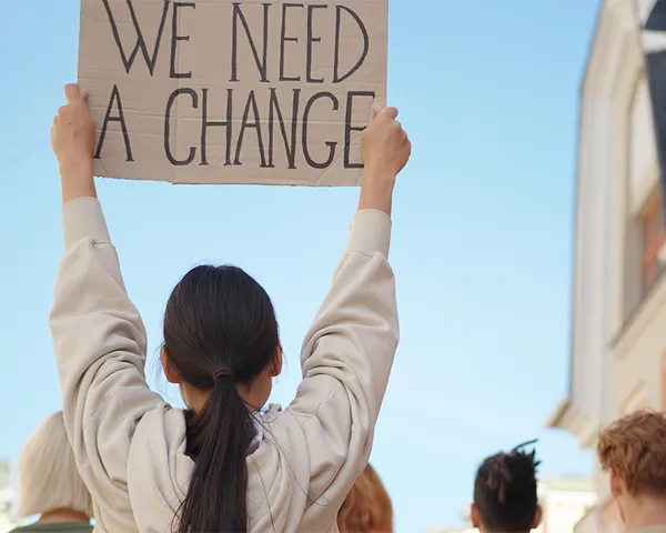 Demonstranter med plakaten "We need a change"