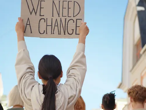Demonstranter med plakaten "We need a change"