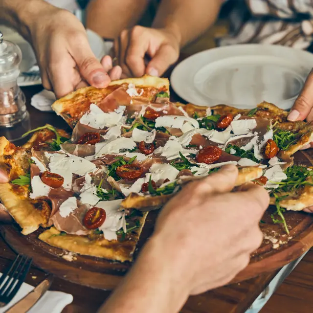 Venner forsyner seg av pizza på en restaurant.