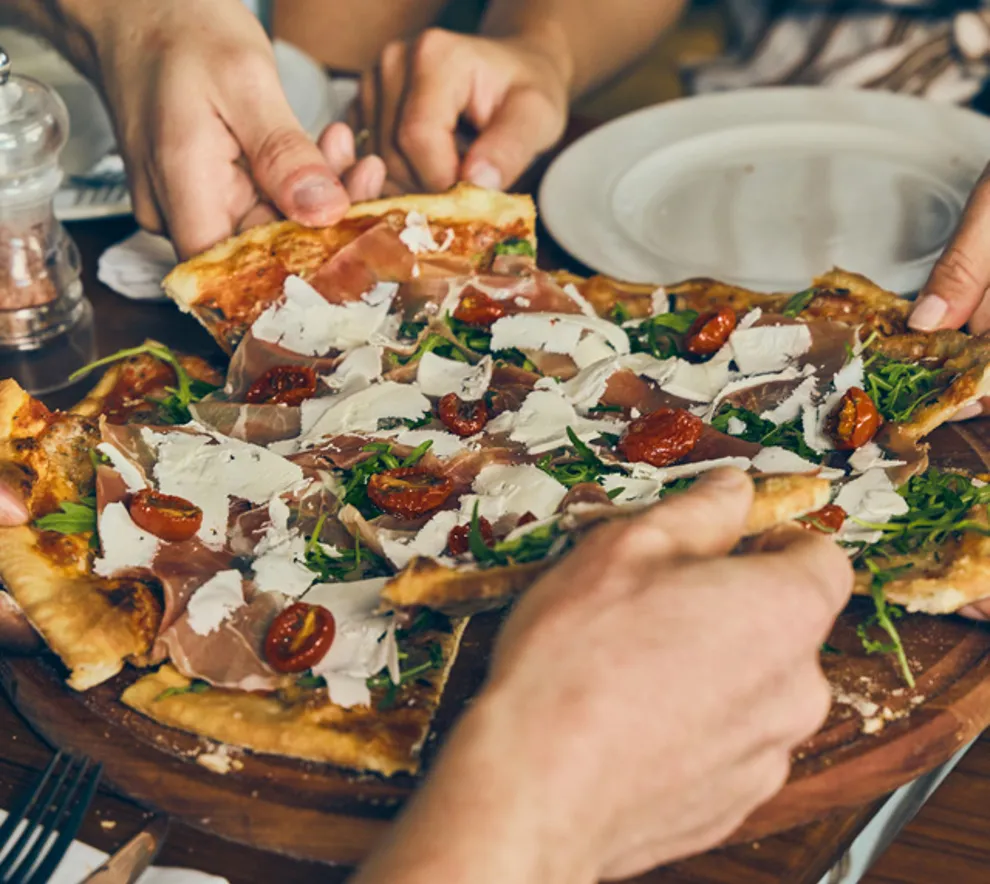 Venner forsyner seg av pizza på en restaurant.