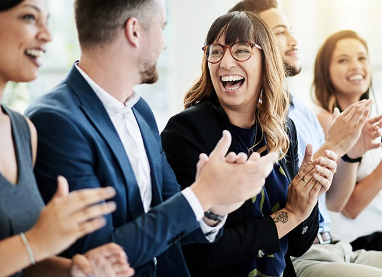 Publikum 3 kvinner og 3 menn som klapper og smiler, formelt kledd