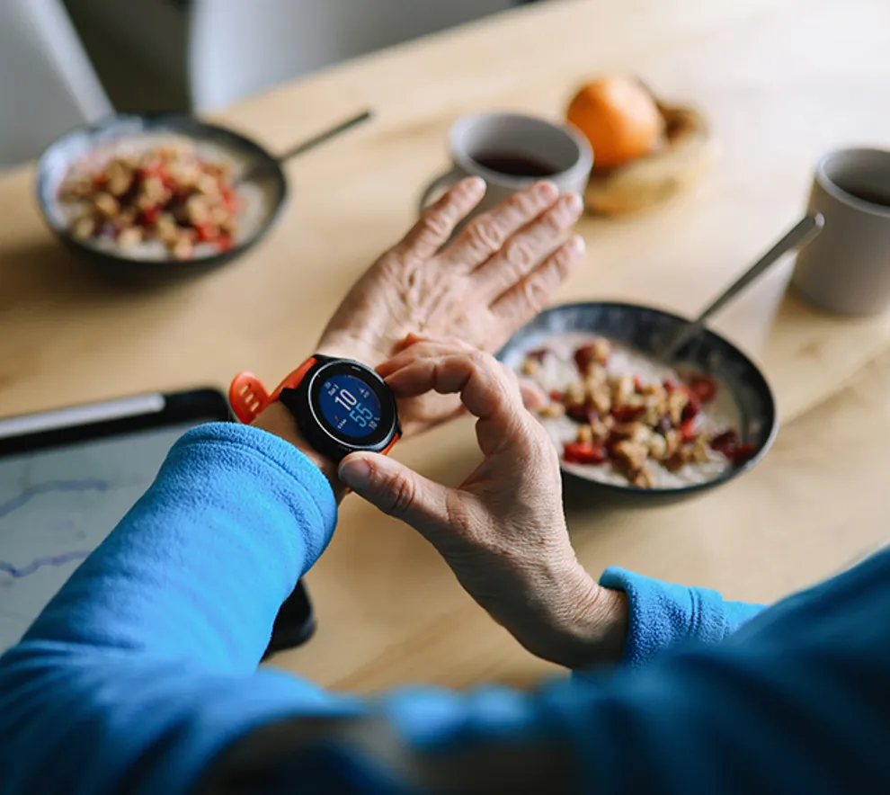 Person sjekker pulsklokke under måltid i hverdagslig helsesituasjon