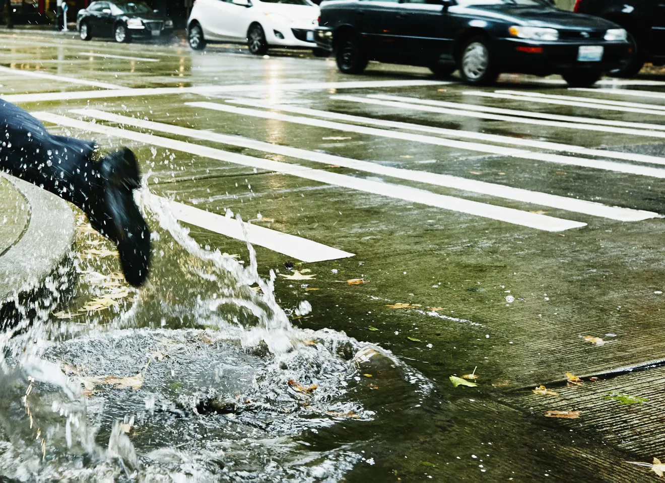 Foto av gate med vann forårsaket av regnvær og ben som løper over fotgjengerovergang