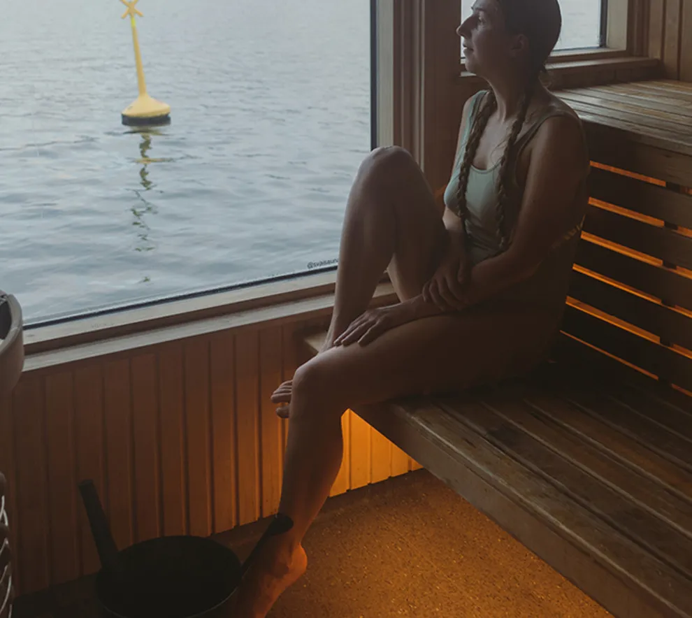 Kvinne sitter i sauna ved sjøen