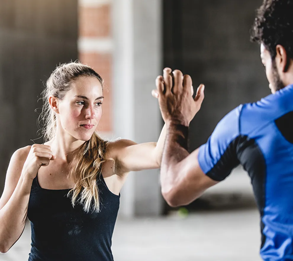 Kvinne trener selvforsvar med instruktør – Krav Maga trening for styrke og selvbeskyttelse.