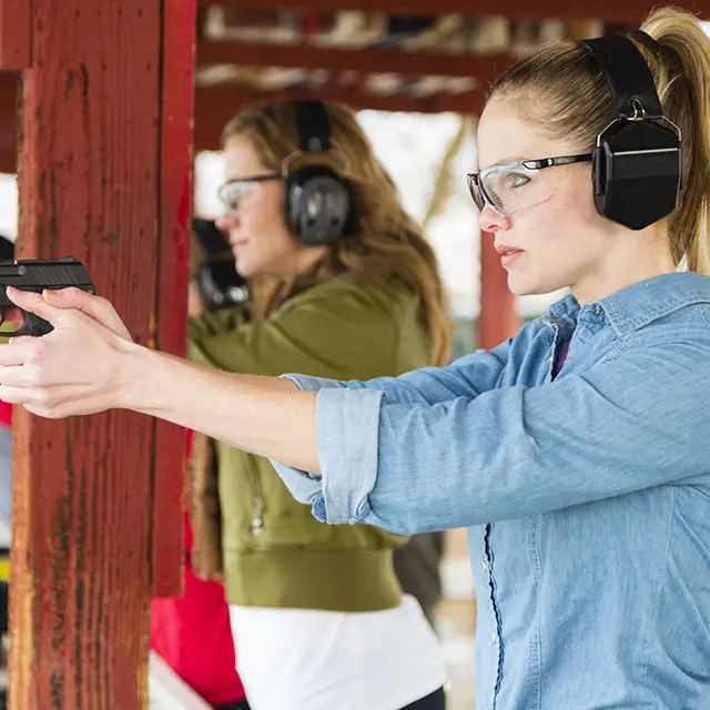 Bilde viser nærbilde av to kvinner som sikter med pistol på skytebane