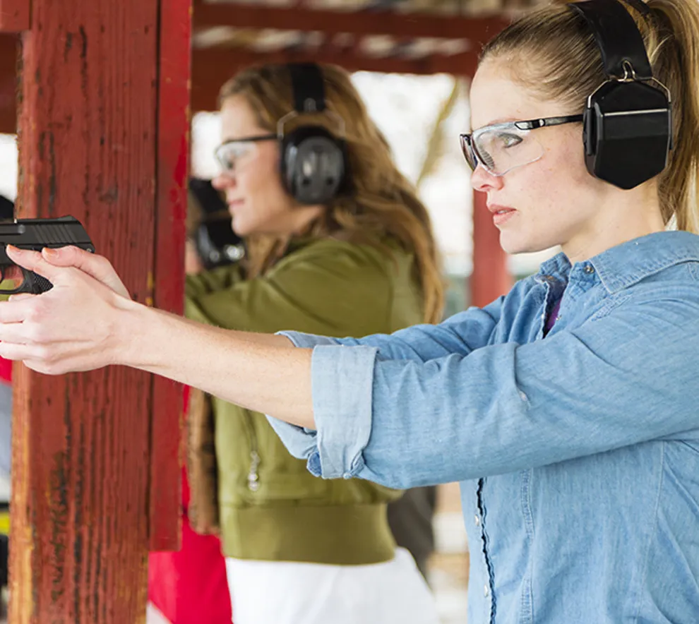 Bilde viser nærbilde av to kvinner som sikter med pistol på skytebane
