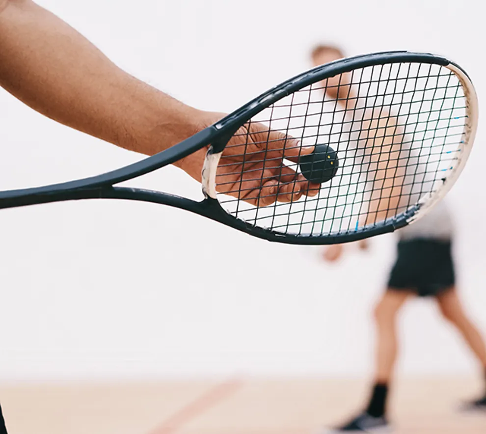 Beskjært bilde av en mann klar til å serve en squashball.