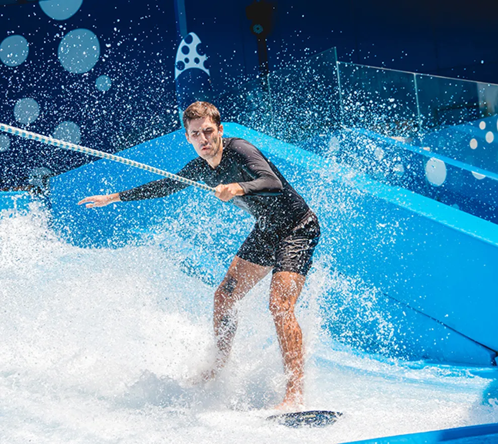 Mann står på surfebrett på en surfebølgemaskin