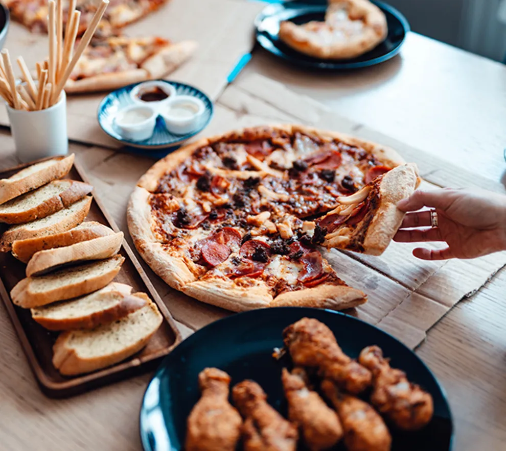 Bilde av middagsbord med pizza,kyllingvinger og brød