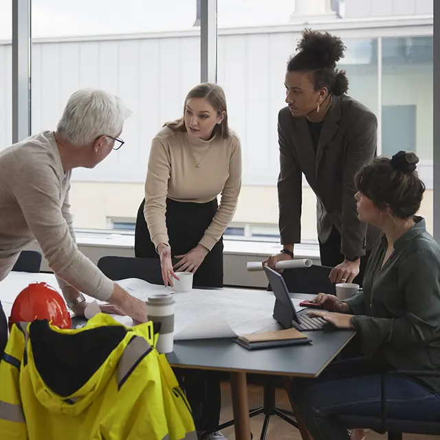 Gruppe ingeniører og prosjektledere i møte om infrastrukturplaner på kontor.