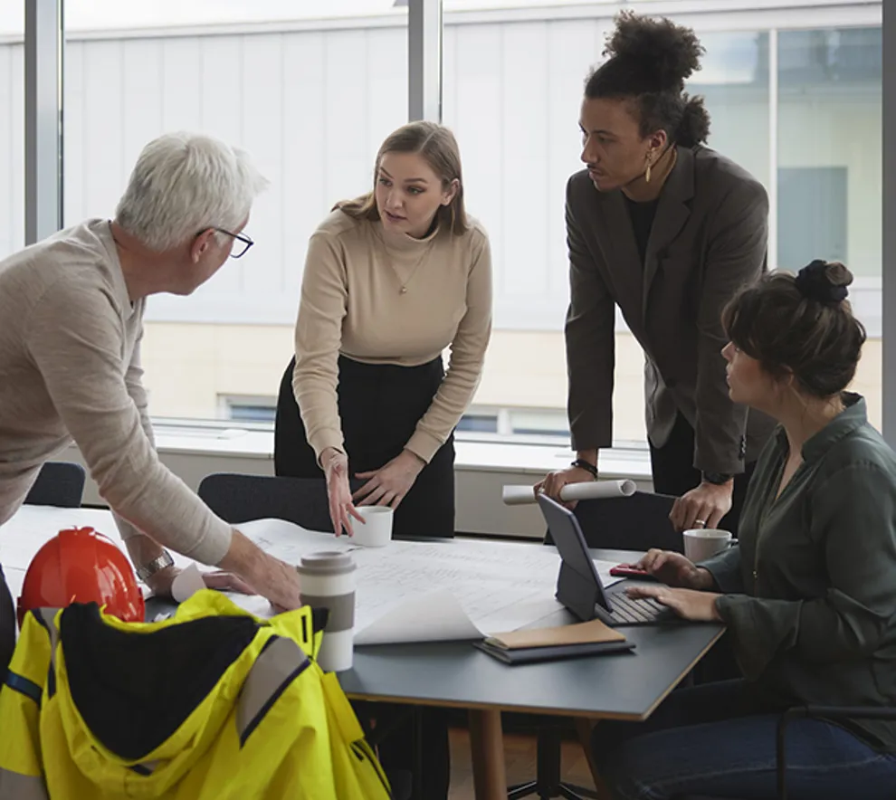 Gruppe ingeniører og prosjektledere i møte om infrastrukturplaner på kontor.