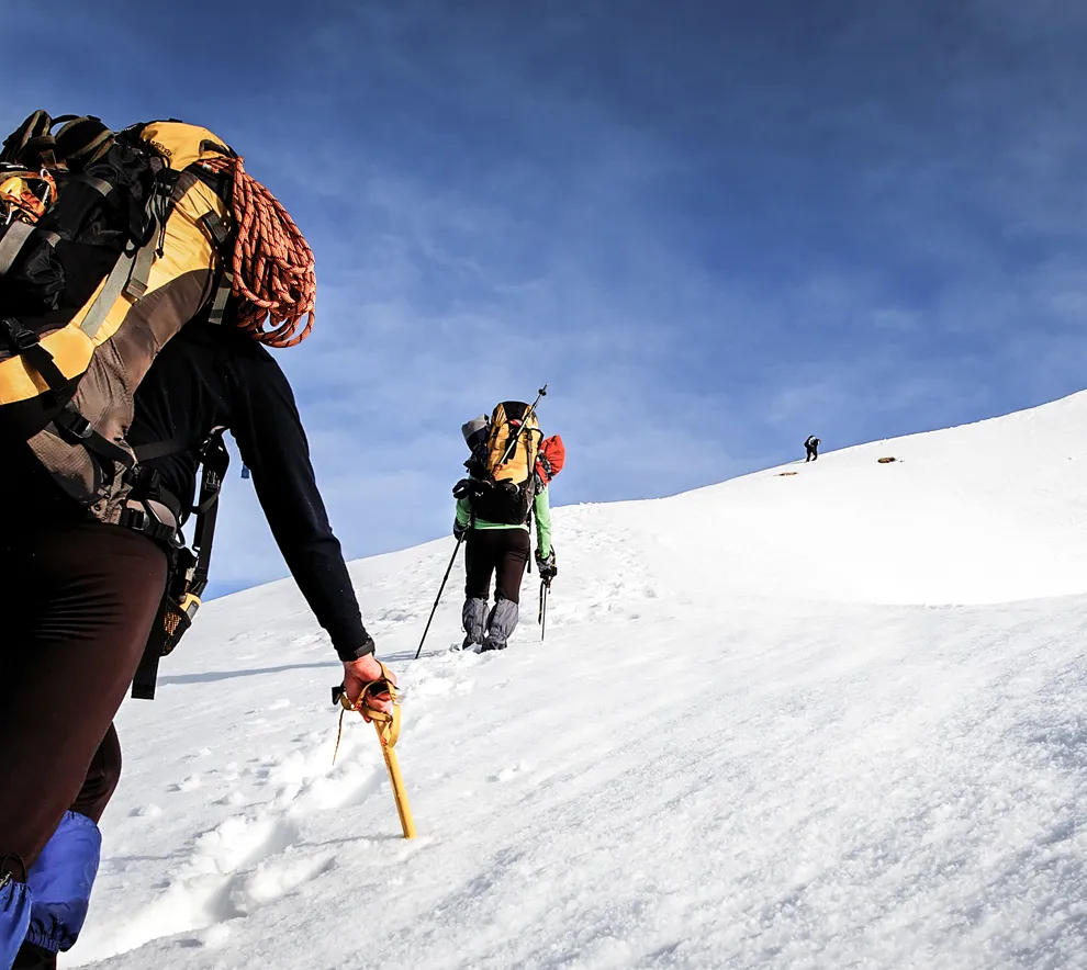 Fire personer bestiger en bratt fjelltopp
