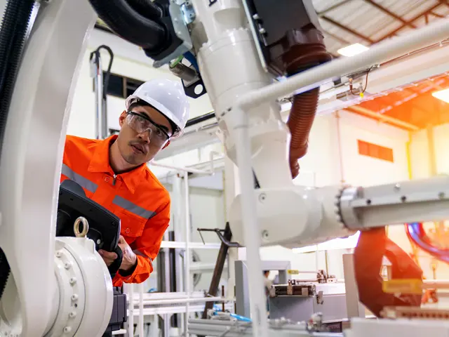 Mann i ført vernehjelm fikser på en robot