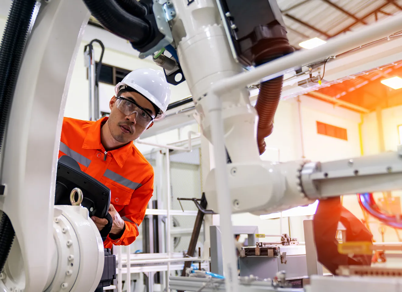 Mann i ført vernehjelm fikser på en robot