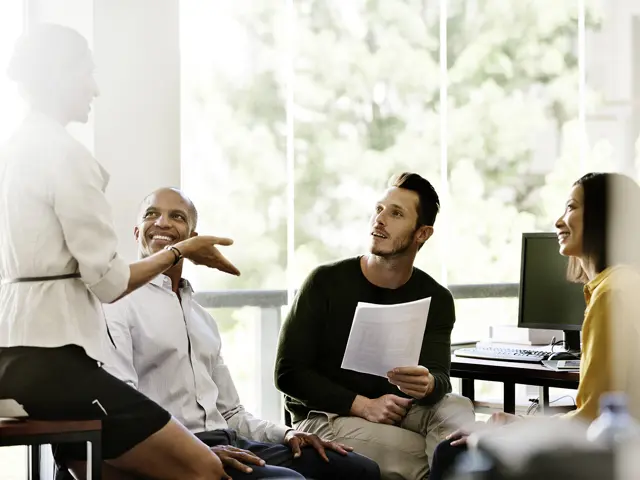 Kvinne som holder en uformell presentasjon, kollegaene følger nøye med.