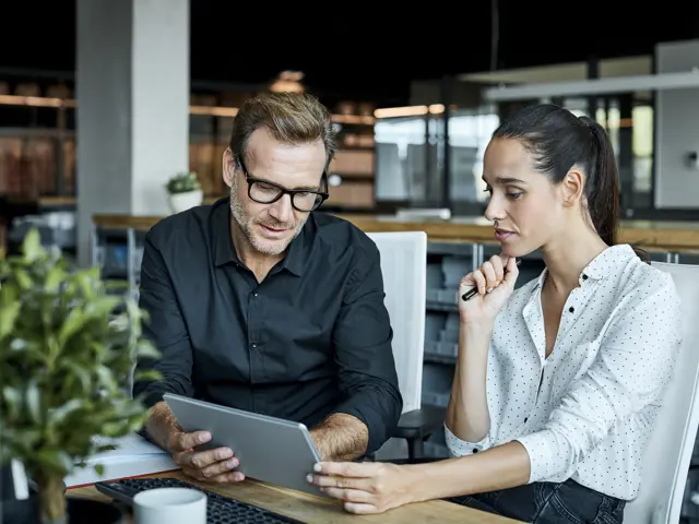 To kollegaer som samarbeider og ser på samme skjerm.