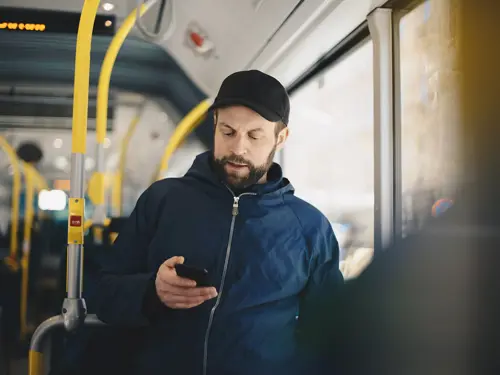 Mann som reiser med buss, ser på en mobil