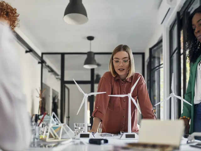 Flere unge kvinner ved et bord med modeller av vindturbiner