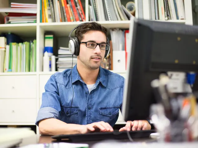 Illustrasjonsbilde av en ung man med headset på og jobber med datamaskin