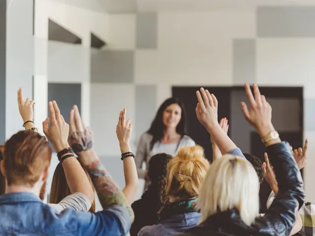 Illustrasjonsbilde av en kvinne på scenen foran et publikum som som rekker opp hender for å stille spørsmål