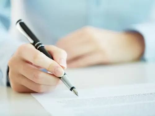 Illustrasjonsbilde av en hånd som holder en pen for å signere på en kontrakt