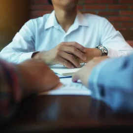 Nærbilde av hender tilhørende en ung mann sittende i et jobbintervju