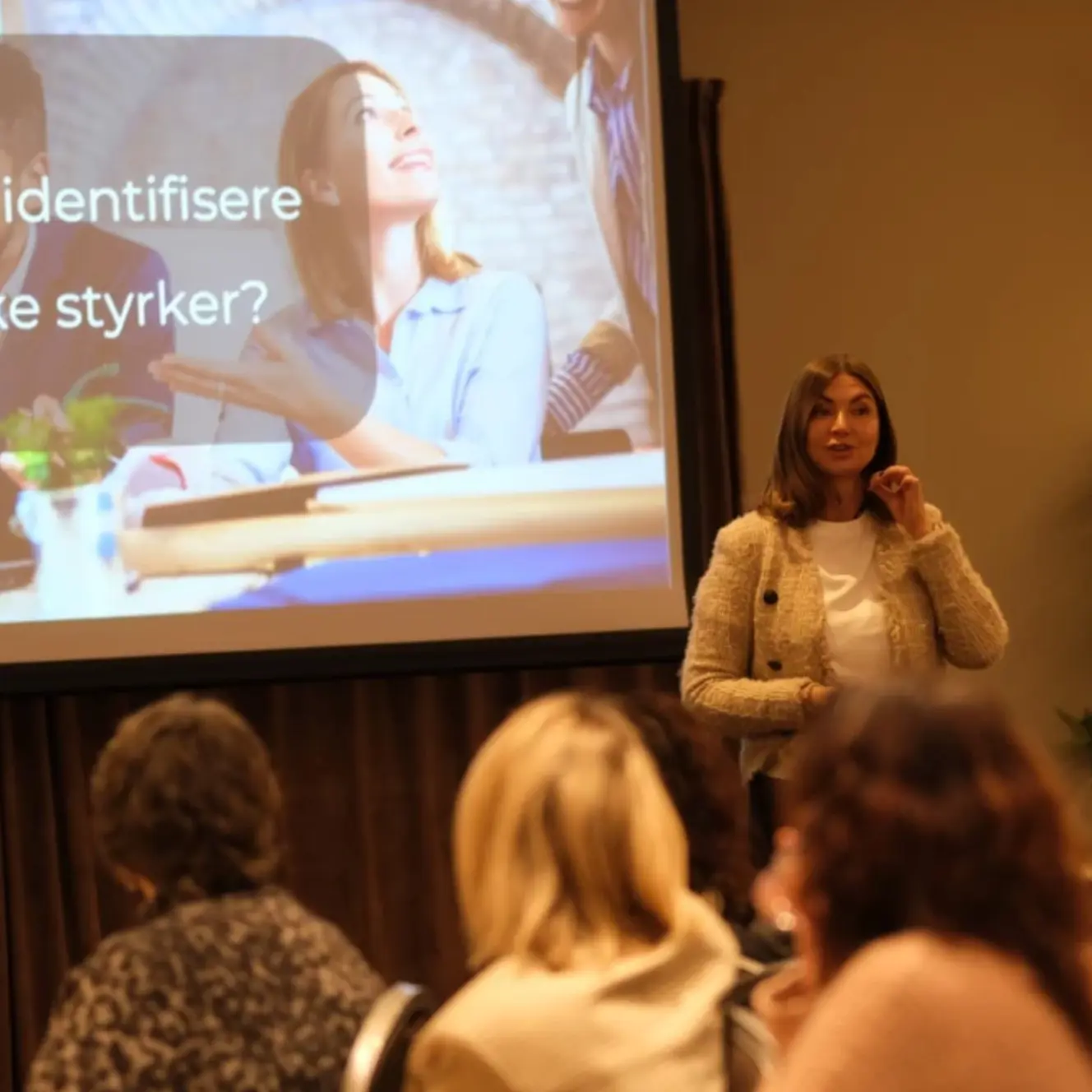 Kvinne som holder foredrag med folk i forgrunen