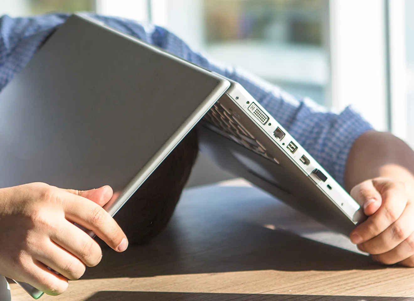 Illustrasjonsbilde av en ansatt sittende på et møtebord som ligger med hode på bordet under en laptop