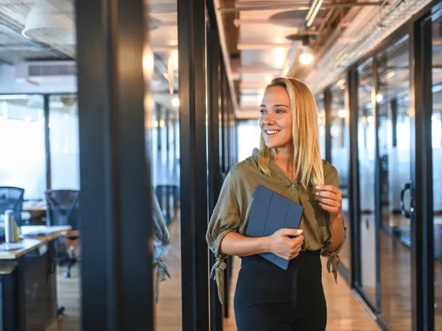 Ung kvinne står i moderne kontorlokaler og ser til høyre