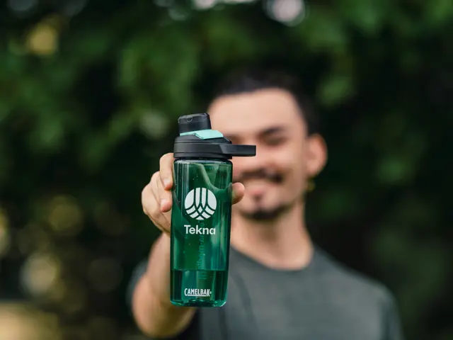 Person med Master som holder en Tekna-drikkeflaske foran seg. 